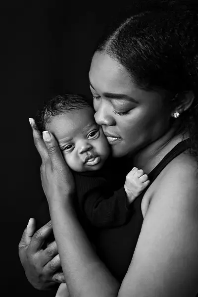 Black and white portrait of a mother lovingly holding and nuzzling her newborn baby, captured by Dia Kiss, a Chicago suburbs photographer.